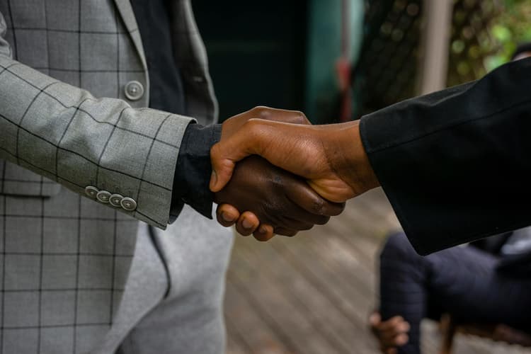 Two people shaking hands to mean people working together
